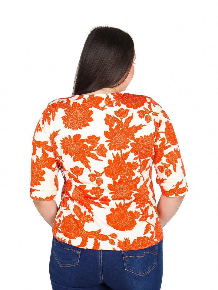 Mujer vistiendo blusa blanca con estampado floral naranja y mangas 3/4.