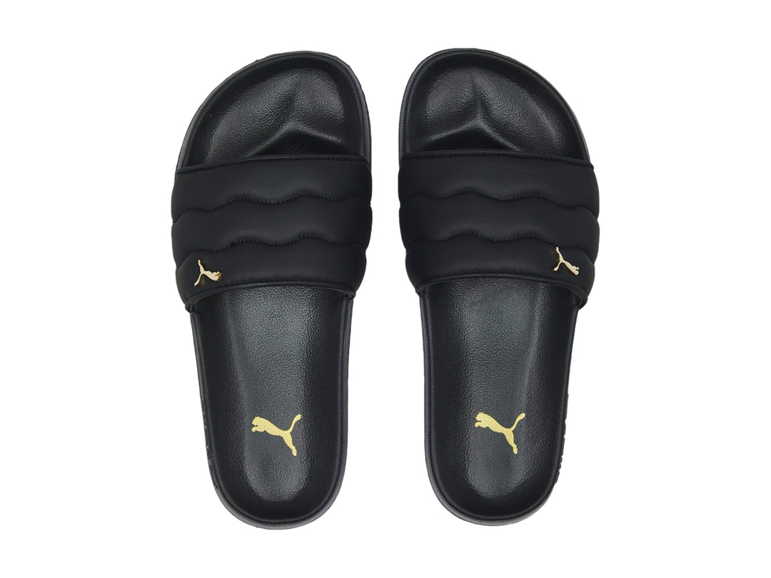 Sandalias PUMA negras con correa acolchada y logotipo dorado.