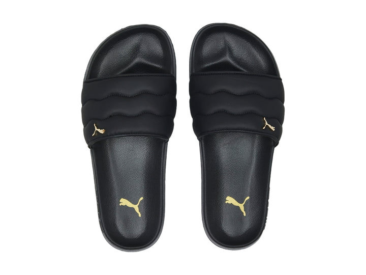 Sandalias PUMA negras con correa acolchada y logotipo dorado.