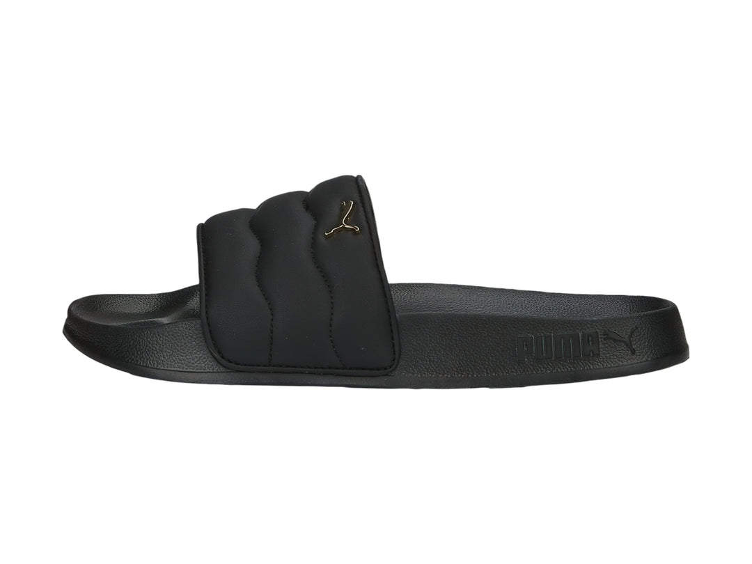 Sandalias PUMA negras con correa acolchada y logotipo dorado.