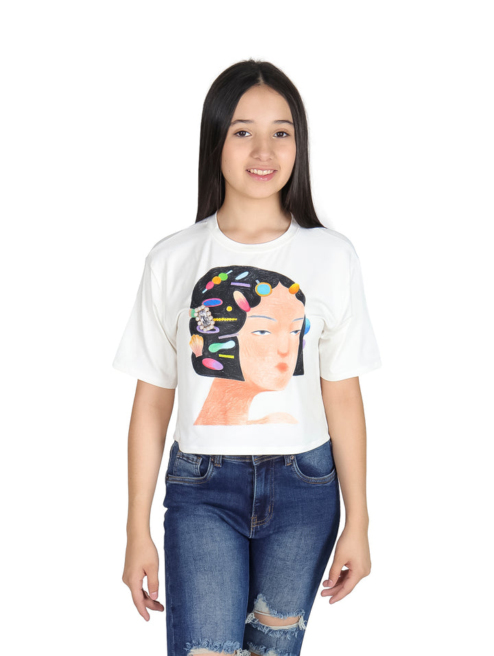 Camiseta blanca crop top para niña con estampado artístico de un rostro y joyas coloridas.