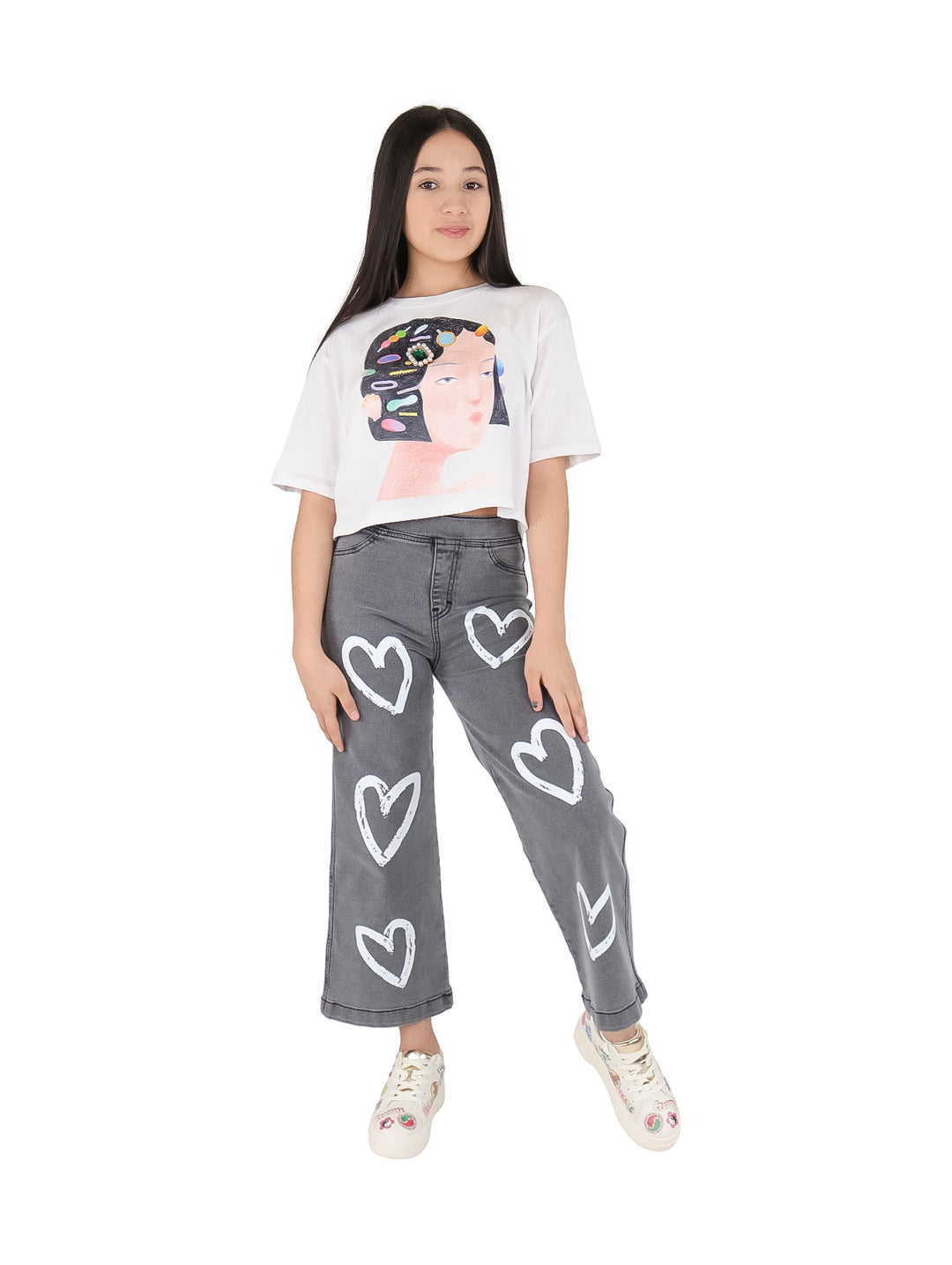 Camiseta blanca crop top para niña con estampado artístico de un rostro y joyas coloridas.
