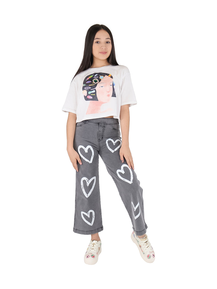 Camiseta blanca crop top para niña con estampado artístico de un rostro y joyas coloridas.