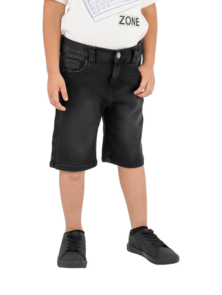 Niño vistiendo un short de mezclilla color negro y calzado negro sobre fondo blanco.