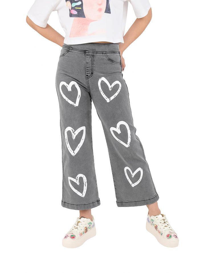 Pantalón de mezclilla gris para niña con estampado de corazones blancos.