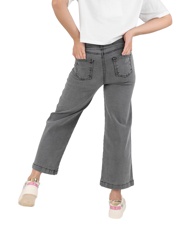 Pantalón de mezclilla gris para niña con estampado de corazones blancos.