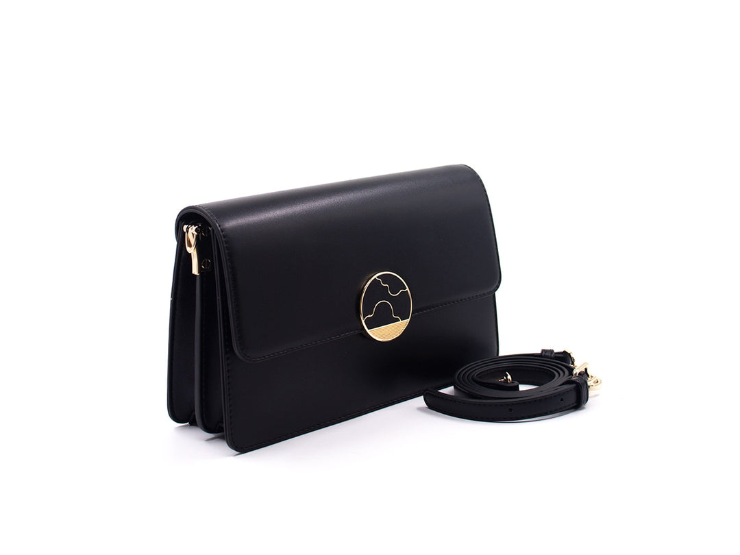 Bolso negro rectangular con cierre circular dorado y correa desmontable sobre fondo blanco.