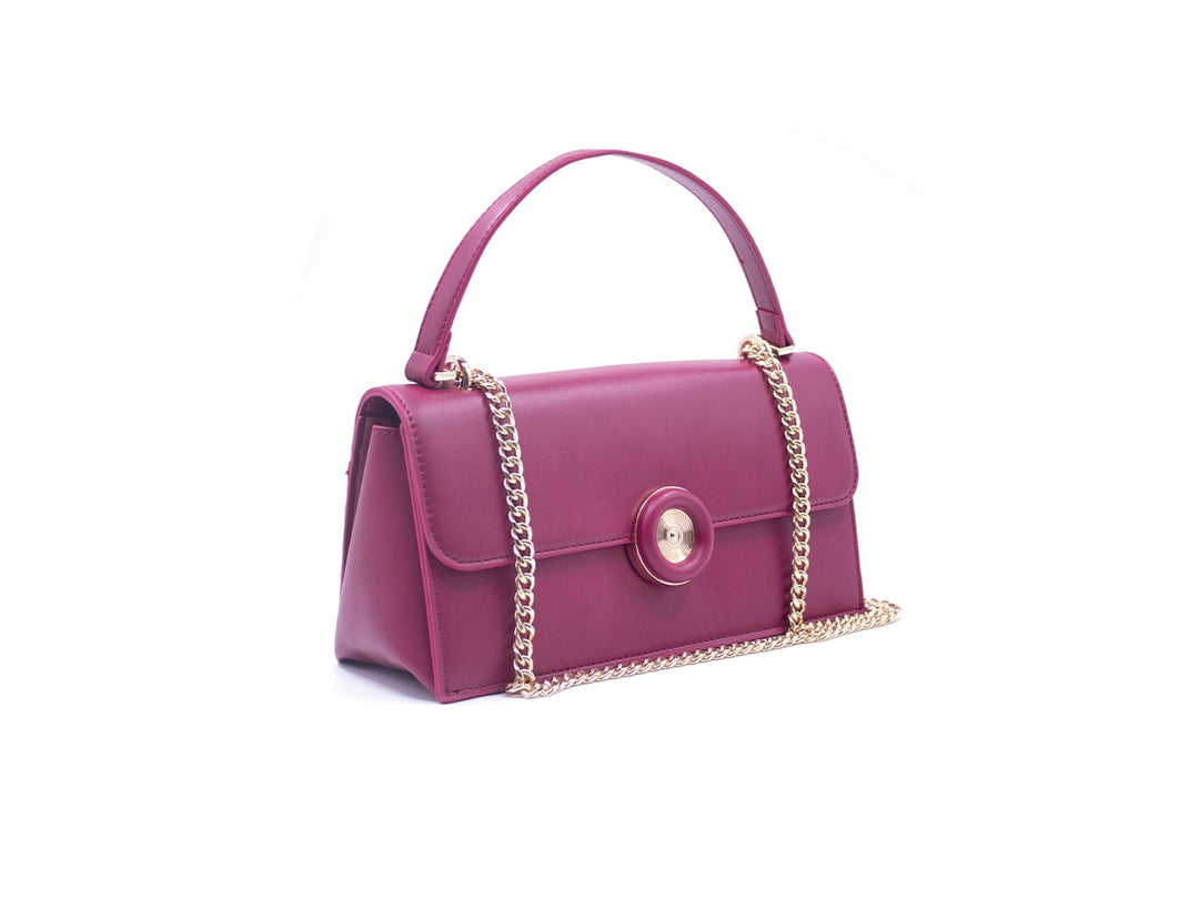 Bolso pequeño color rosa quemado con asa superior y correa de cadena dorada con cierre circular central.