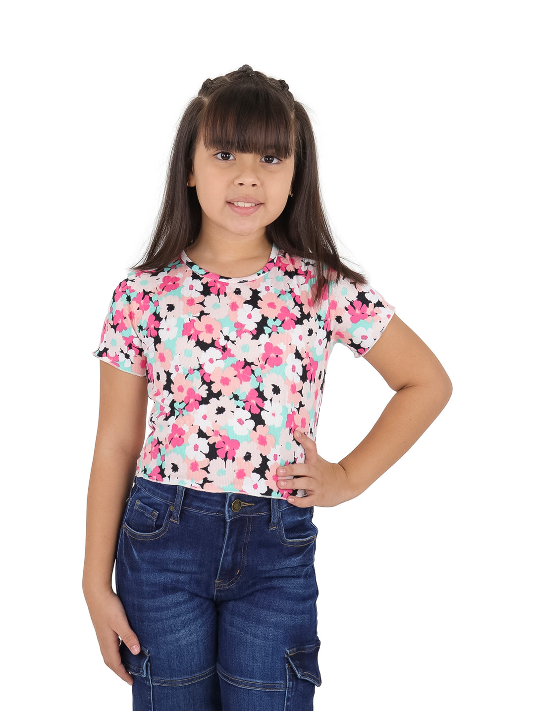 Niña vistiendo blusa blanca con estampado floral rosa y pantalones vaqueros azules.