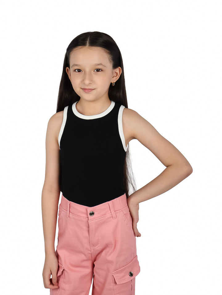 Niña vistiendo blusa negra sin mangas con ribete blanco y pantalones rosas.