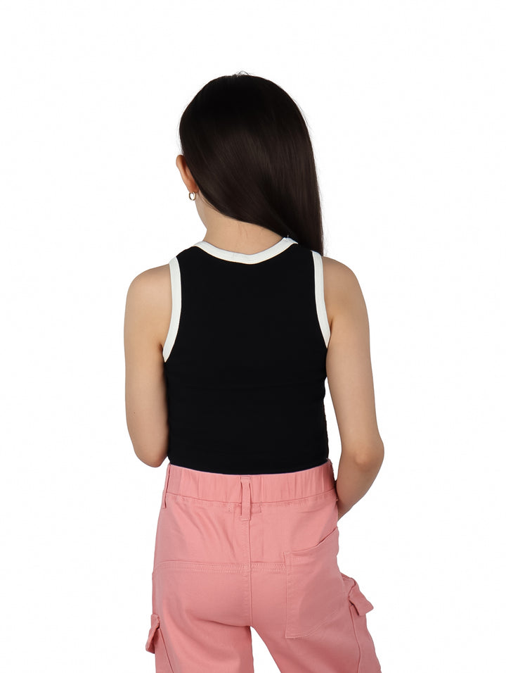 Niña vistiendo blusa negra sin mangas con ribete blanco y pantalones rosas.