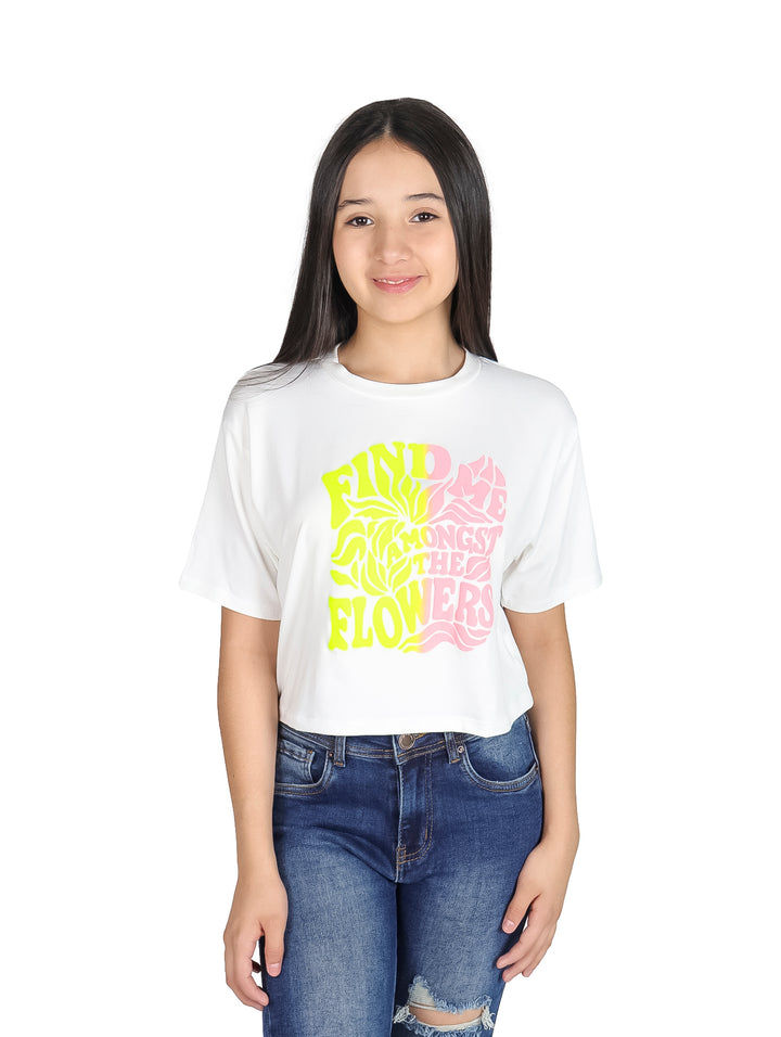Niña con camiseta blanca de manga corta y estampado colorido de letras y flores.