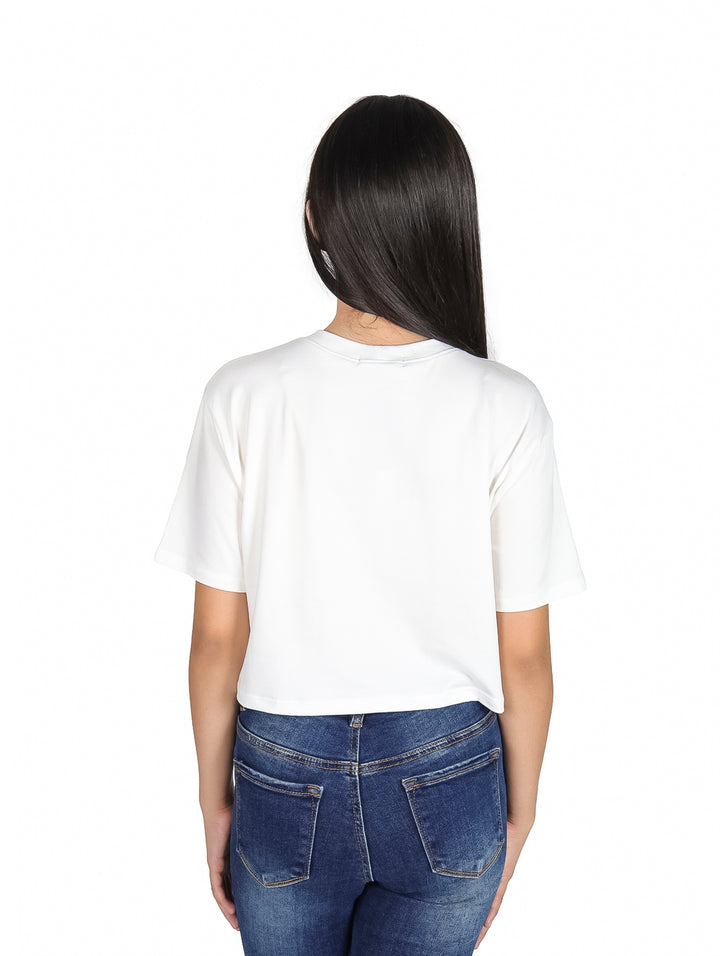 Niña con camiseta blanca de manga corta y estampado colorido de letras y flores.