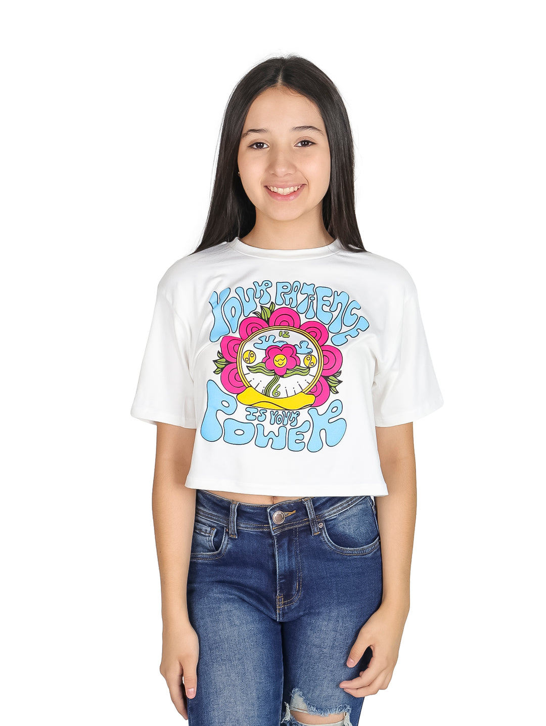 Niña vistiendo camiseta crop blanca con estampado colorido estilo años 70 y jeans azules.