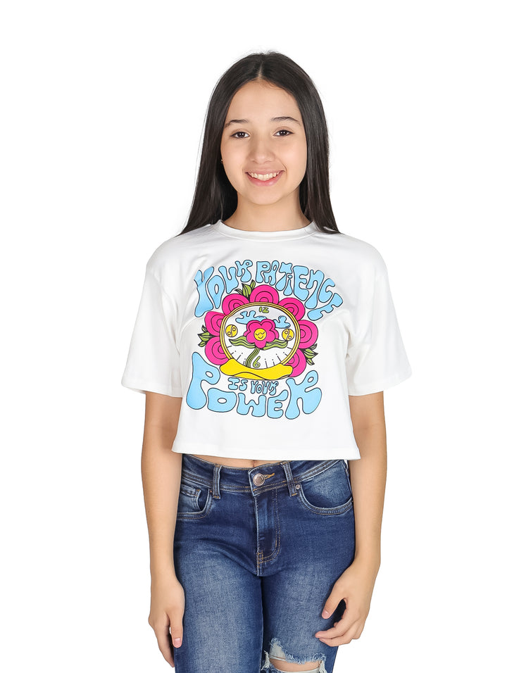 Niña vistiendo camiseta crop blanca con estampado colorido estilo años 70 y jeans azules.