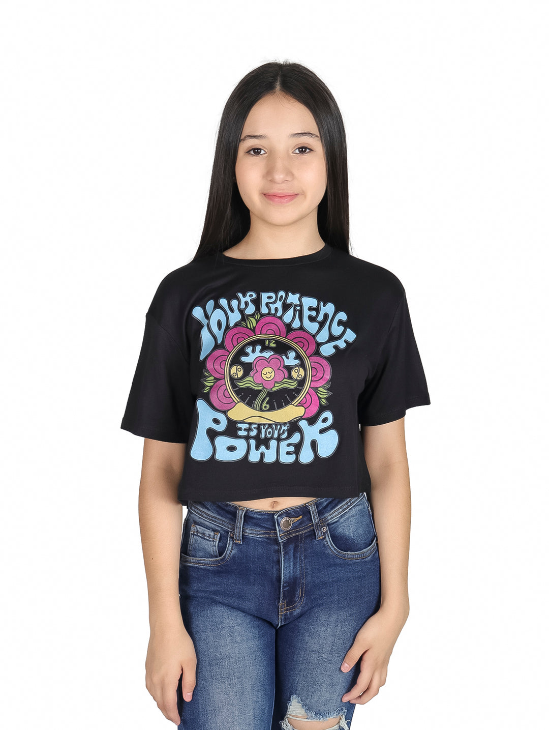Niña vistiendo camiseta crop top negra con estampado colorido estilo años 70 y jeans azules.