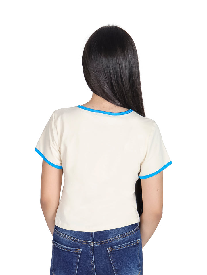 Niña vistiendo camiseta corta color crema con estampado de sirena y bordes en color azul.