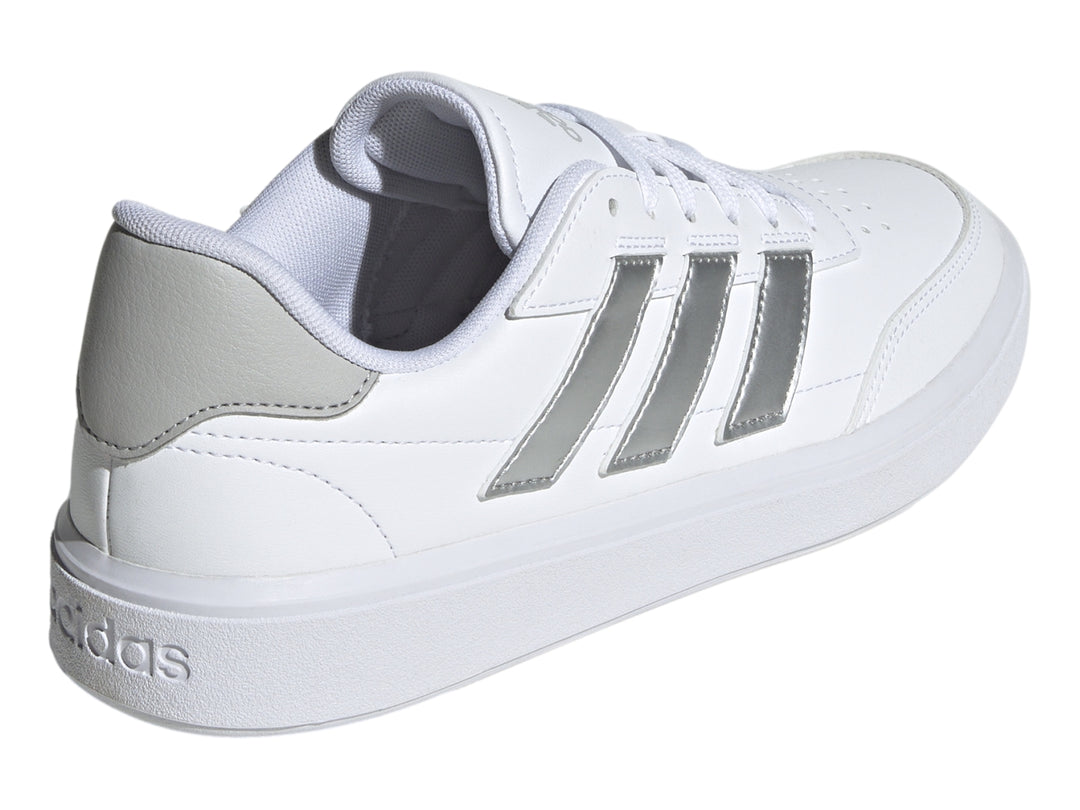 Tenis Adidas blancos con tres franjas plateadas y detalle gris en el talón.