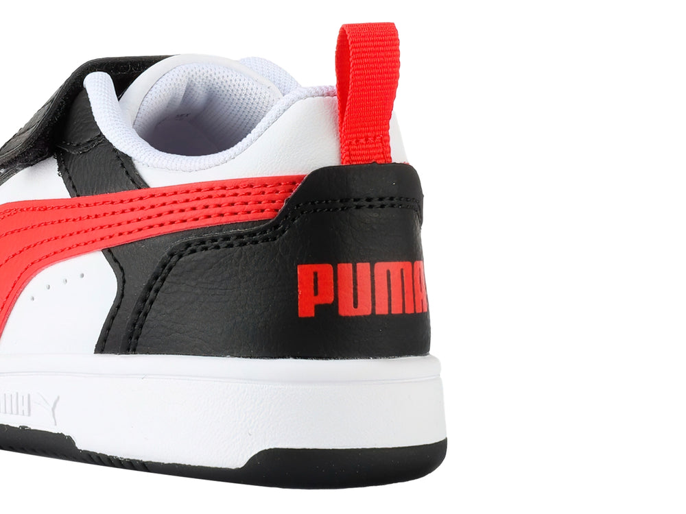 Tenis PUMA Rebound V6 Lo AC+PS en colores blanco, negro y rojo con cierre de velcro para niños.