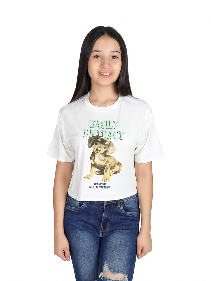 Niña vistiendo una camiseta blanca con estampado de un perro y texto en color verde.