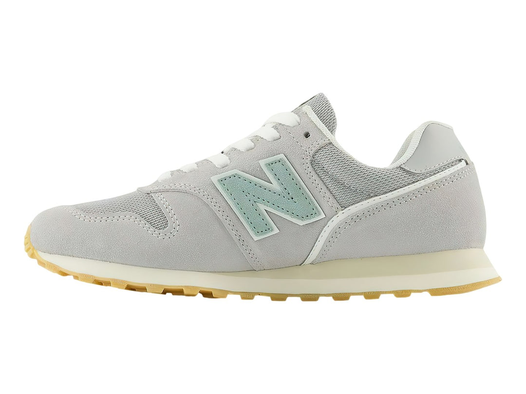 Tenis New Balance 373 color gris Raincloud con detalles en azul claro y suela color goma.