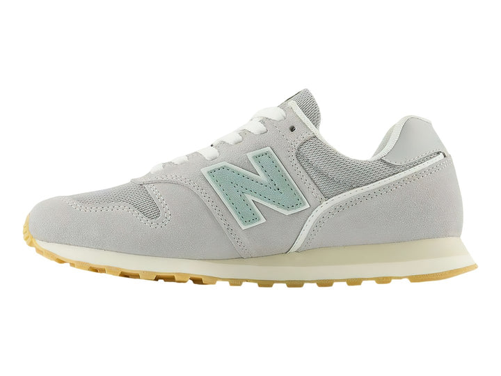 Tenis New Balance 373 color gris Raincloud con detalles en azul claro y suela color goma.