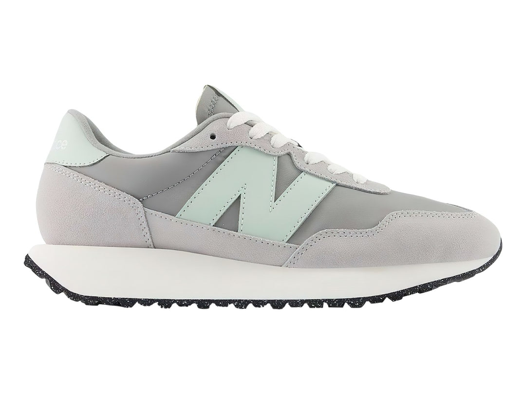 Tenis New Balance color gris pizarra con suela blanca y detalles en verde menta.