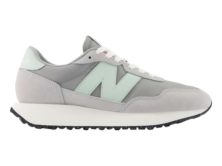 Tenis New Balance color gris pizarra con suela blanca y detalles en verde menta.