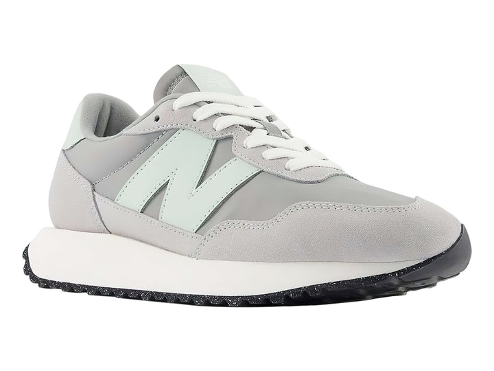 Tenis New Balance color gris pizarra con suela blanca y detalles en verde menta.