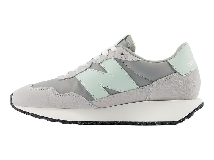 Tenis New Balance color gris pizarra con suela blanca y detalles en verde menta.