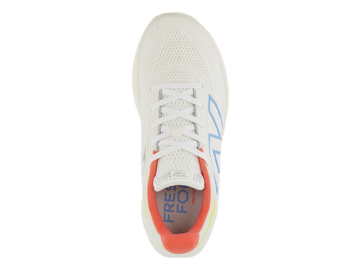 Tenis New Balance color blanco con detalles en azul, amarillo y coral, diseñados para correr.