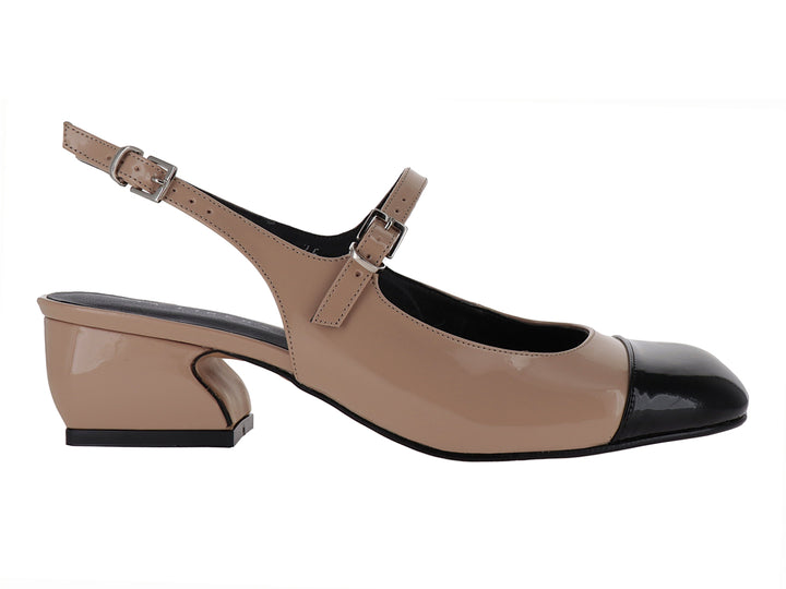 Zapato de tacón bajo en color nude con punta negra brillante y correa ajustable al tobillo.