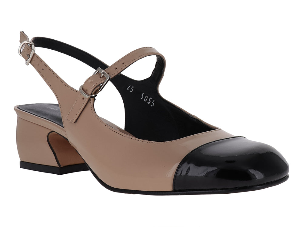 Zapato de tacón bajo en color nude con punta negra brillante y correa ajustable al tobillo.