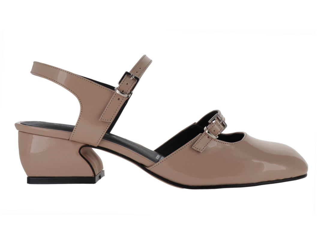 Zapato de charol sintético color nude con tacón bajo y correa ajustable al tobillo.