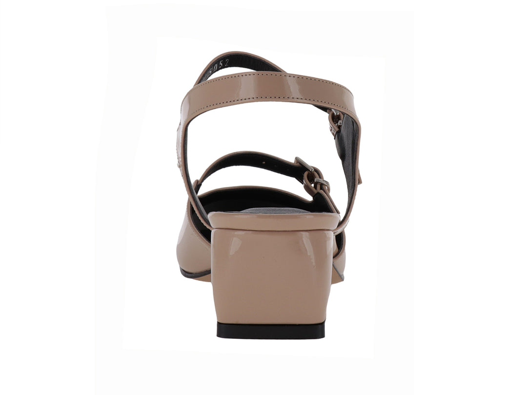 Zapato de charol sintético color nude con tacón bajo y correa ajustable al tobillo.