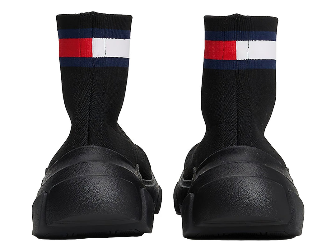 Tenis botín tipo calcetín color negro con suela gruesa y franja tricolor en el tobillo.