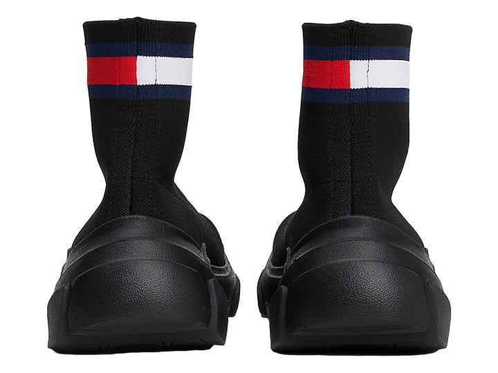 Tenis botín tipo calcetín color negro con suela gruesa y franja tricolor en el tobillo.