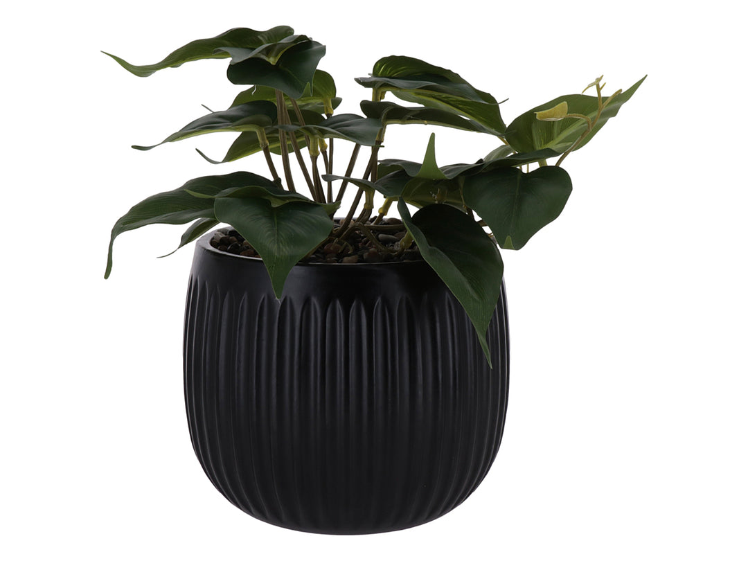 Planta artificial verde en maceta decorativa negra con textura acanalada.
