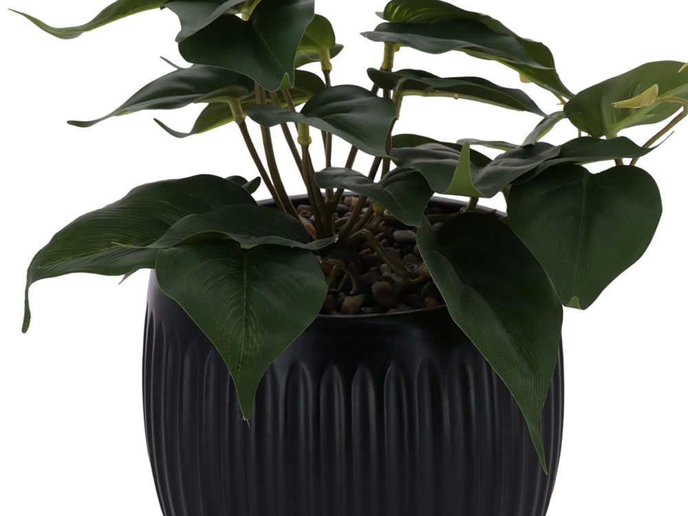 Planta artificial verde en maceta decorativa negra con textura acanalada.