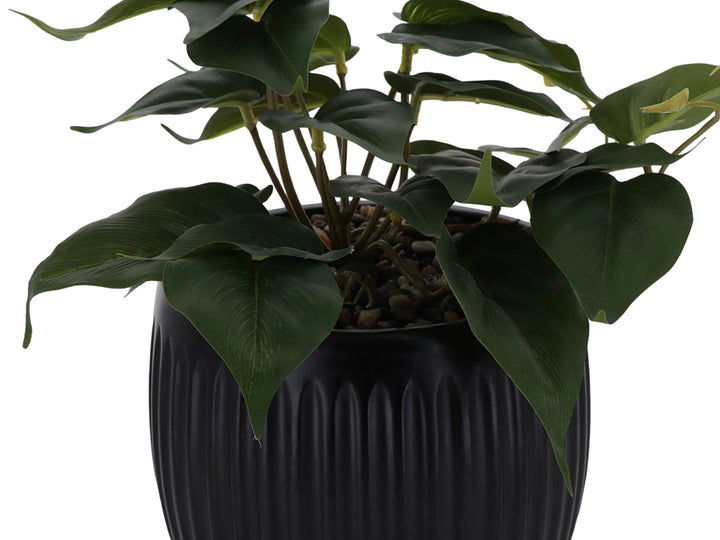Planta artificial verde en maceta decorativa negra con textura acanalada.