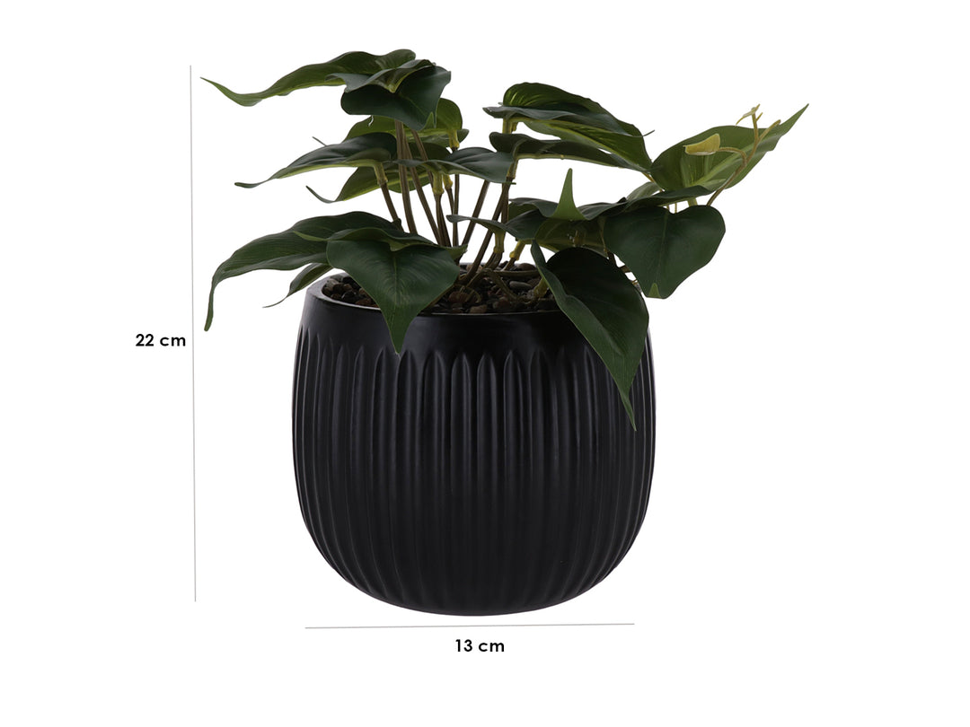 Planta artificial verde en maceta decorativa negra con textura acanalada.