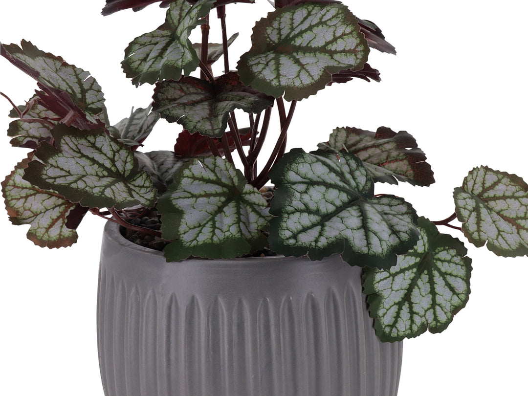 Planta artificial con hojas verdes y rojas en maceta de dolomita gris acanalada.