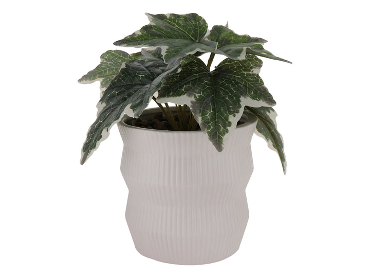 Planta artificial con hojas verdes en maceta de cerámica blanca con textura de rayas verticales.