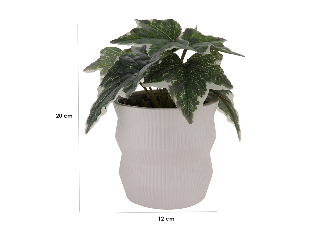Planta artificial con hojas verdes en maceta de cerámica blanca con textura de rayas verticales.