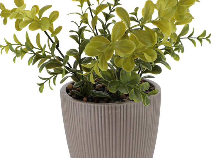 Planta artificial verde en maceta decorativa de dolomita color beige con textura acanalada.