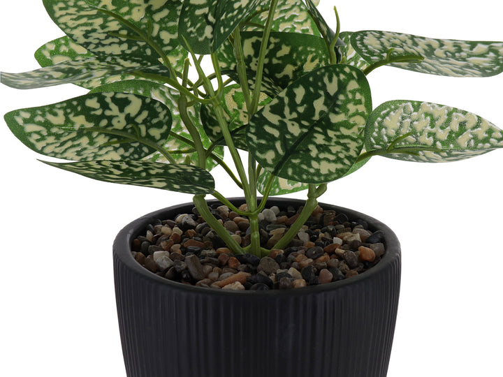 Planta artificial con hojas verdes y blancas en maceta decorativa de color negro acanalada.