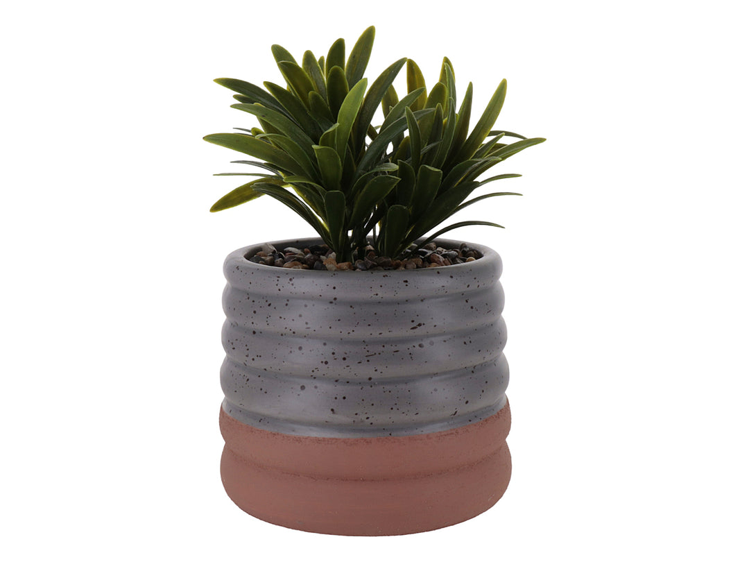 Planta artificial en maceta de cerámica gris con diseño ondulado y base color terracota.