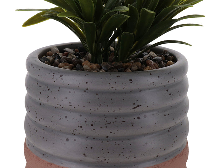Planta artificial en maceta de cerámica gris con diseño ondulado y base color terracota.