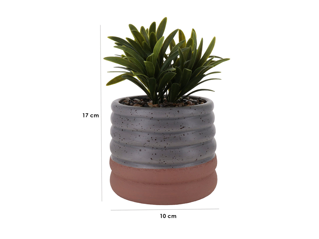 Planta artificial en maceta de cerámica gris con diseño ondulado y base color terracota.