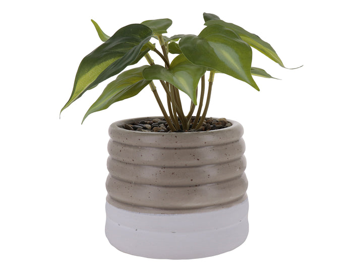 Planta artificial verde en maceta decorativa de cerámica color beige con diseño ondulado y base blanca.